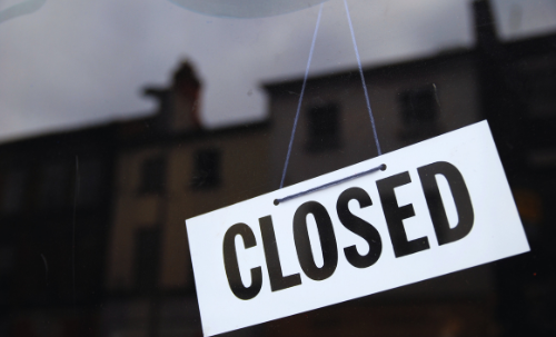 White sign Sign in window with black font that reads: Closed